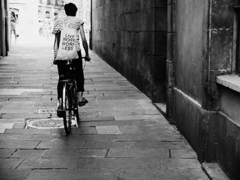 Rear view of girl cycling on street amidst buildings