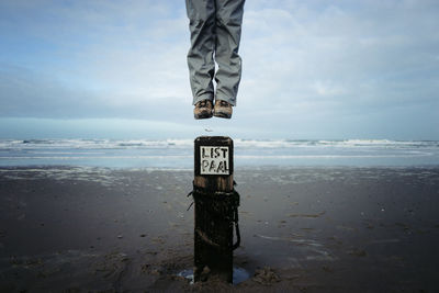 Low section of person with text on beach against sky