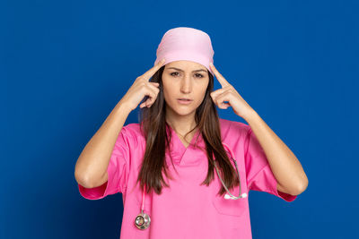 Portrait of beautiful young woman standing against pink blue background