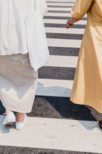 Low section of man and woman walking on crosswalk