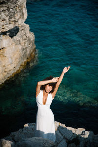 Woman standing on rock by sea