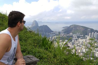 Man looking at cityscape and sea against sky