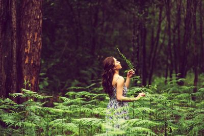 Young woman sitting on tree in forest