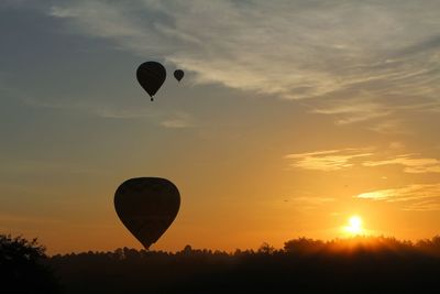 Silhouette hot air balloon flying against sky during sunset