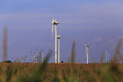 Wind turbines on field against sky