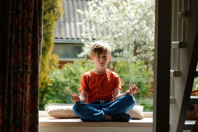 Rear view of boy looking through window