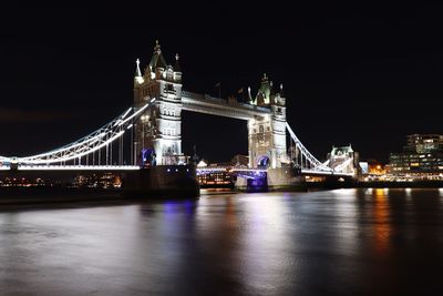 Illuminated bridge over river at night