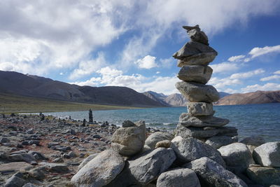 Stack of pebbles on shore against sky