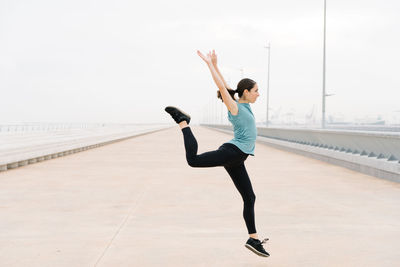 Full length of woman with arms raised standing against sky