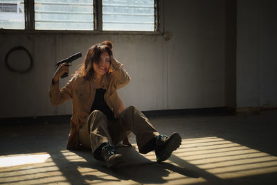 Young woman sitting on floor against window