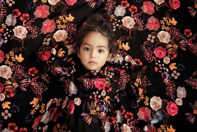 Portrait of cute girl against floral curtain