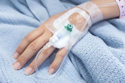 Cropped hand of woman with iv drip attached in hospital