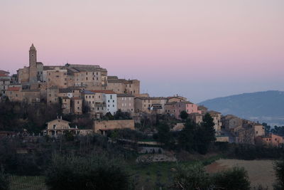 Buildings in town against sky at sunset