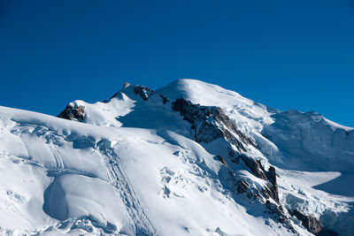 Scenic view of snowcapped mountains against clear blue sky