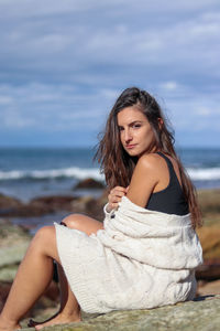 Portrait of young woman sitting at beach
