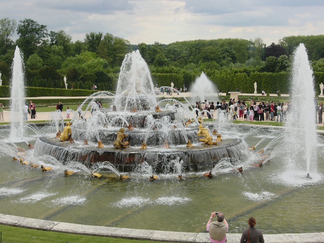 fountain, water, large group of people, motion, leisure activity, splashing, lifestyles, spraying, park - man made space, tourism, travel destinations, enjoyment, famous place, tourist, vacations, mixed age range, fun, day, sky, flowing water, outdoors, nature