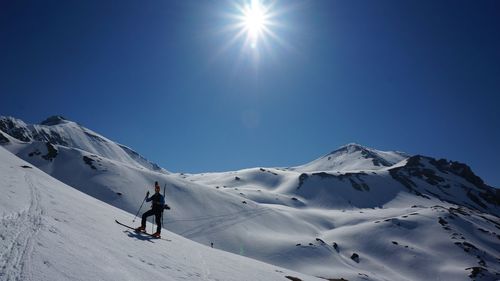 Man skiing on snowcapped mountain against clear sky