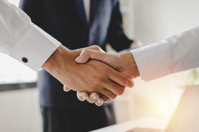 Cropped image of businessmen shaking hands in office