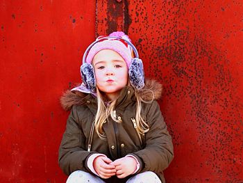 Portrait of girl puckering while sitting against metallic wall