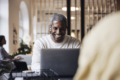 Happy businessman doing video call through laptop while sitting at office