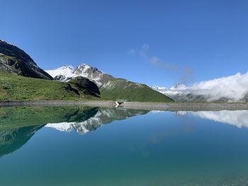 Scenic view of lake and mountains against blue sky