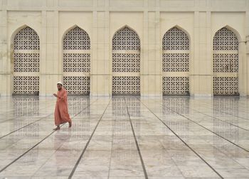 Full length of man walking on floor against building