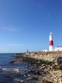 Lighthouse on beach against blue sky