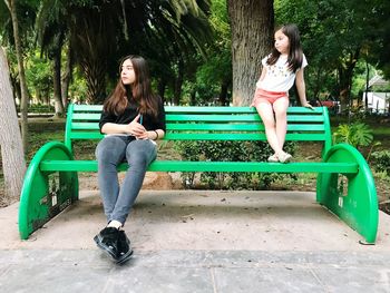 Full length of woman sitting on bench in park