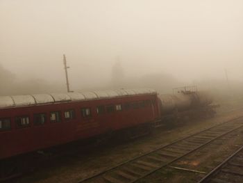 Train on railroad tracks against sky during foggy weather