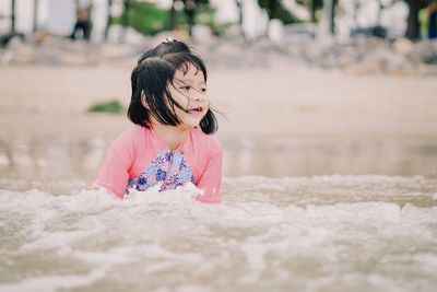 Close-up of cute girl with pink petals on land