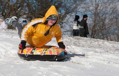 Smiling woman sliding on snow covered field