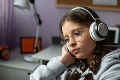 A young brunette girl focused on listening to music on wireless headphones.