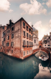 Reflection of buildings in canal against sky