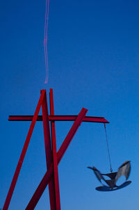 Low angle view of crane against clear blue sky