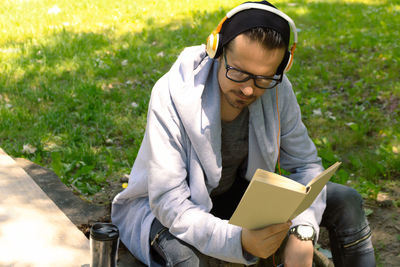 Young man wearing eyeglasses sitting on grass