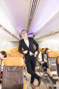 In the plane, there is a young passenger. portrait of a man standing in an airplane aisle