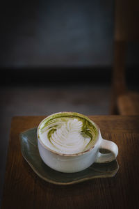 Vertical of fresh matcha green tea late art on wooden background.