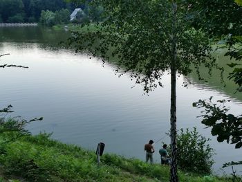 People by lake against trees