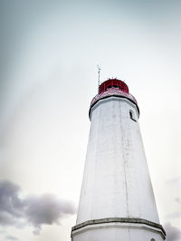 Low angle view of lighthouse by building against sky