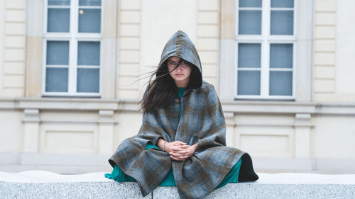 Young woman sitting in front of building