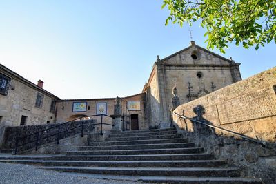 Low angle view of steps amidst buildings against clear blue sky