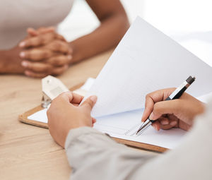 Midsection of woman writing in book at table