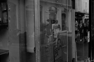 Reflection of man photographing on glass window