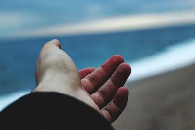 Close-up of human hand against sky