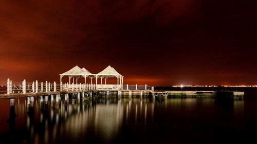 Pier over sea against sky at night