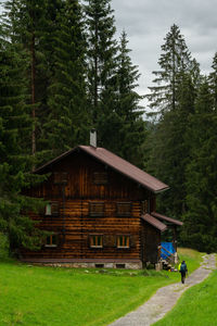 House amidst trees and plants in forest against sky