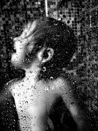 Water drops on glass against boy bathing in bathroom