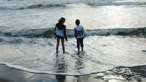 Rear view of friends standing at beach