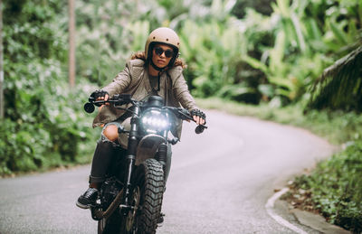 Portrait of woman riding motorcycle on road