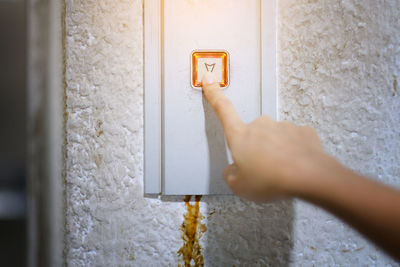 Cropped hand pressing elevator button on wall